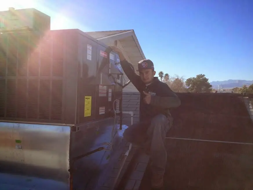 HVAC technician performing Air Duct Cleaning on a rooftop unit in East Grand Rapids